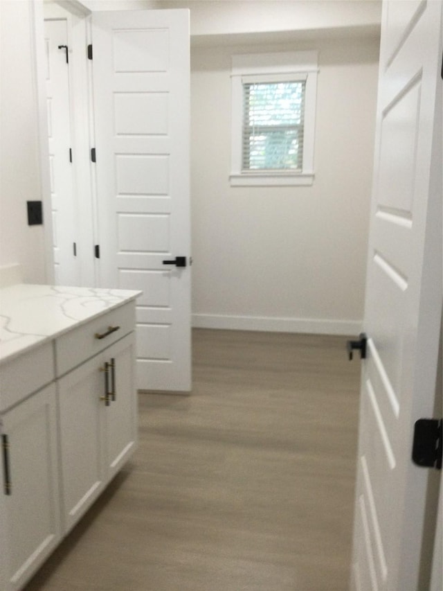 bathroom featuring vanity, wood finished floors, and baseboards