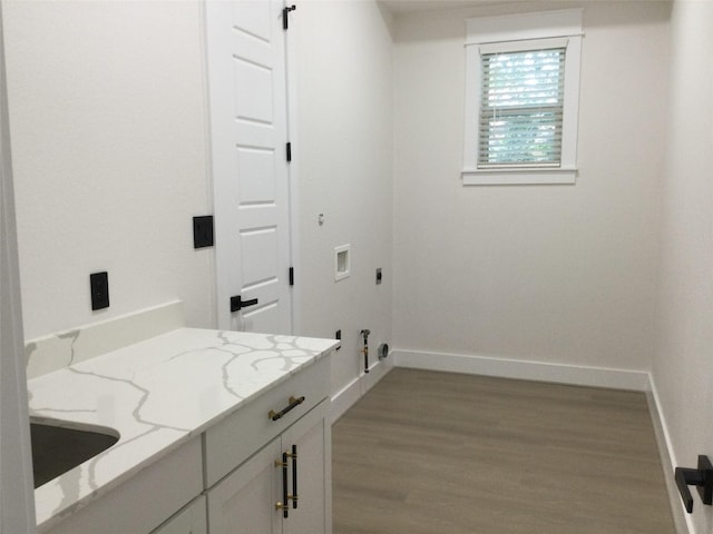 washroom with baseboards, a barn door, washer hookup, wood finished floors, and cabinet space