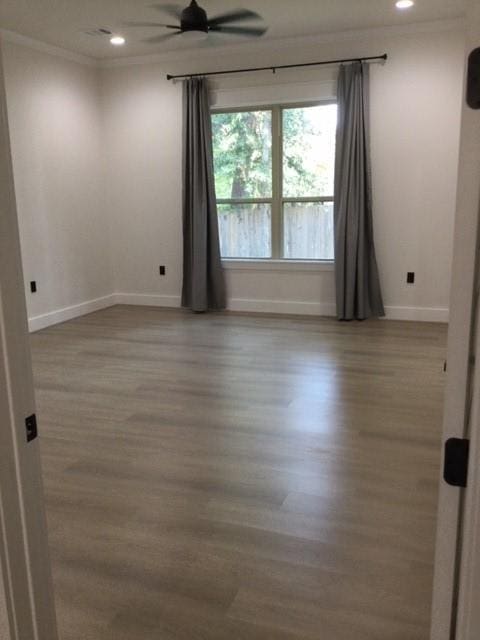 empty room with recessed lighting, wood finished floors, baseboards, and ornamental molding