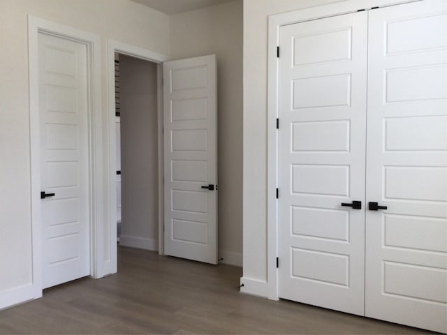 unfurnished bedroom featuring a closet, baseboards, and wood finished floors