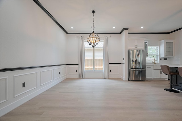 11706 Walden Rd, Montgomery, TX 77356 - unfurnished dining area featuring ornamental molding, light wood-style flooring, and a decorative wall