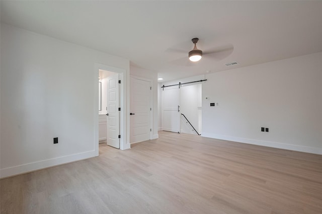 11706 Walden Rd, Montgomery, TX 77356 - empty room featuring visible vents, light wood-style floors, baseboards, ceiling fan, and a barn door