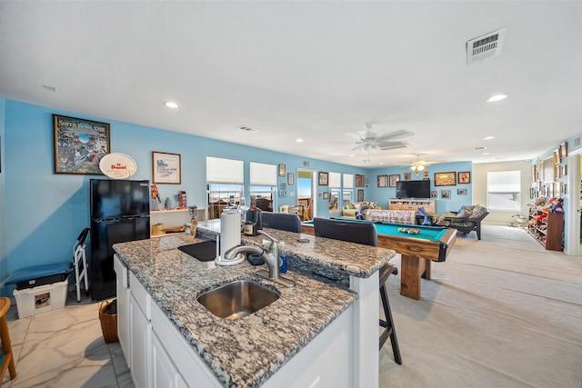 kitchen featuring visible vents, light stone countertops, freestanding refrigerator, marble finish floor, and a sink