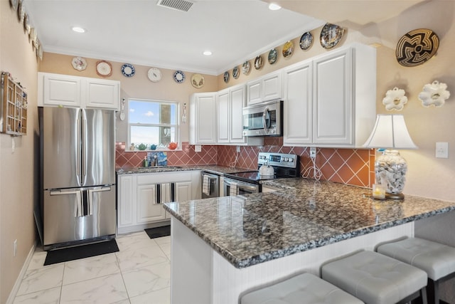 kitchen featuring dark stone countertops, a peninsula, stainless steel appliances, decorative backsplash, and marble finish floor