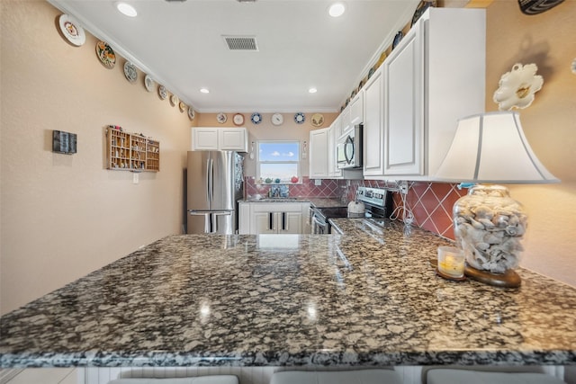 kitchen with visible vents, dark stone counters, ornamental molding, decorative backsplash, and stainless steel appliances