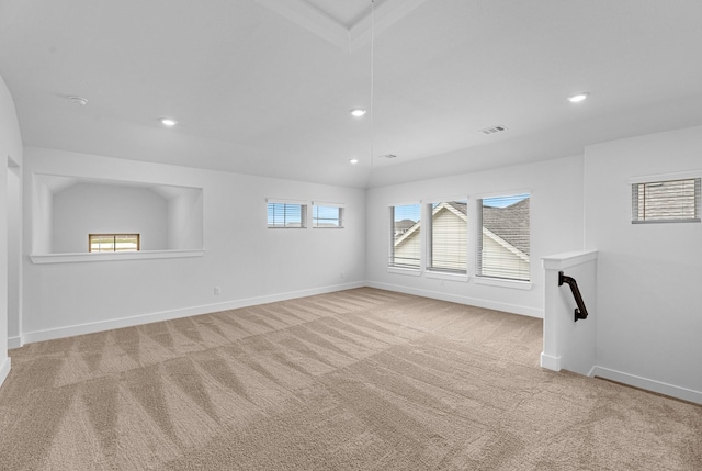 carpeted spare room with attic access, baseboards, visible vents, and a wealth of natural light