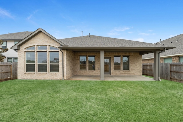 rear view of house featuring a yard, a patio, brick siding, and a fenced backyard