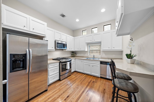 kitchen featuring visible vents, white cabinetry, stainless steel appliances, and a sink