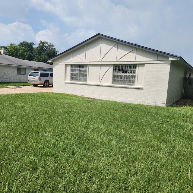 view of side of home with brick siding and a lawn