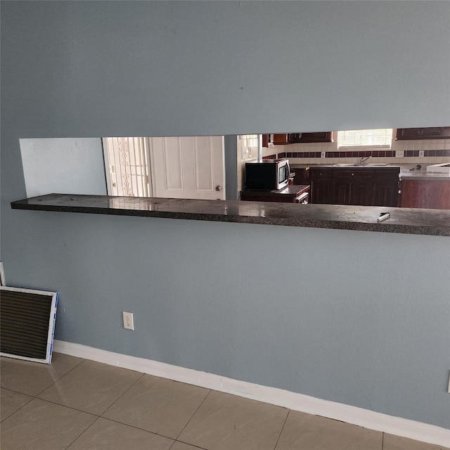 kitchen featuring stainless steel microwave, baseboards, tile patterned floors, and a sink