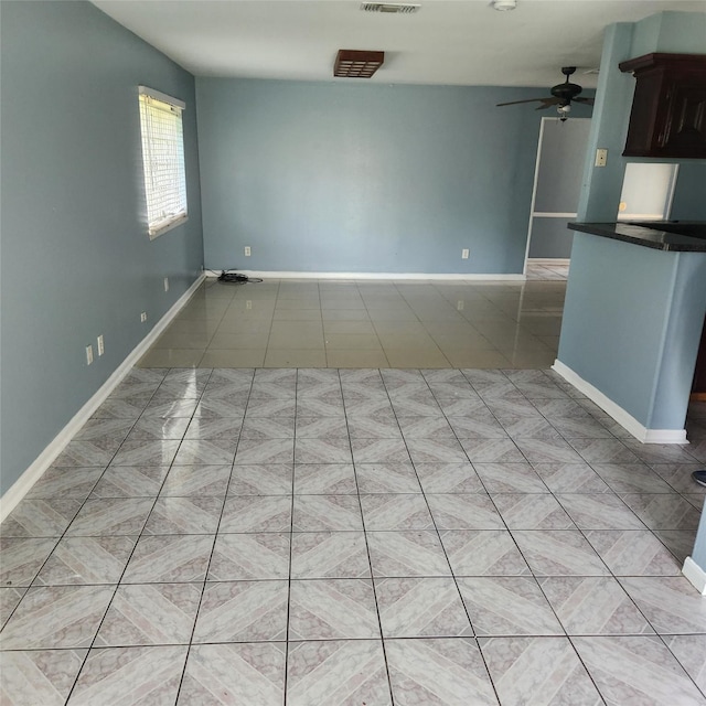 empty room with light tile patterned floors, visible vents, baseboards, and ceiling fan