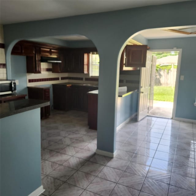 kitchen featuring stainless steel microwave, a healthy amount of sunlight, baseboards, and extractor fan