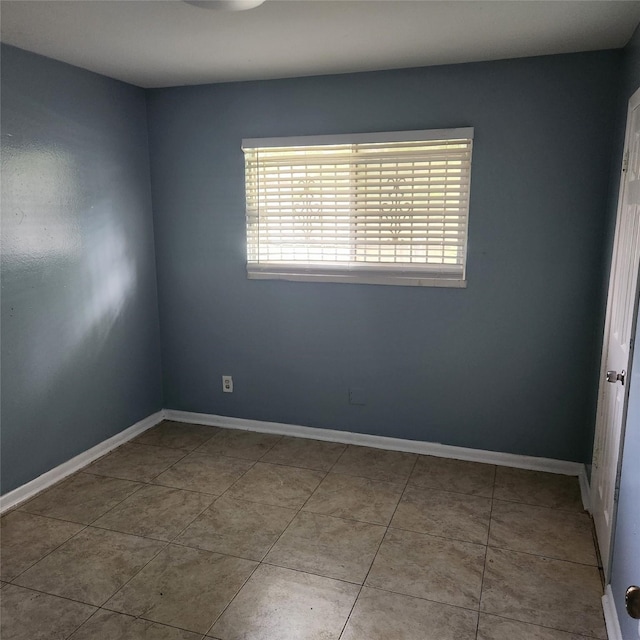 unfurnished room with tile patterned floors and baseboards