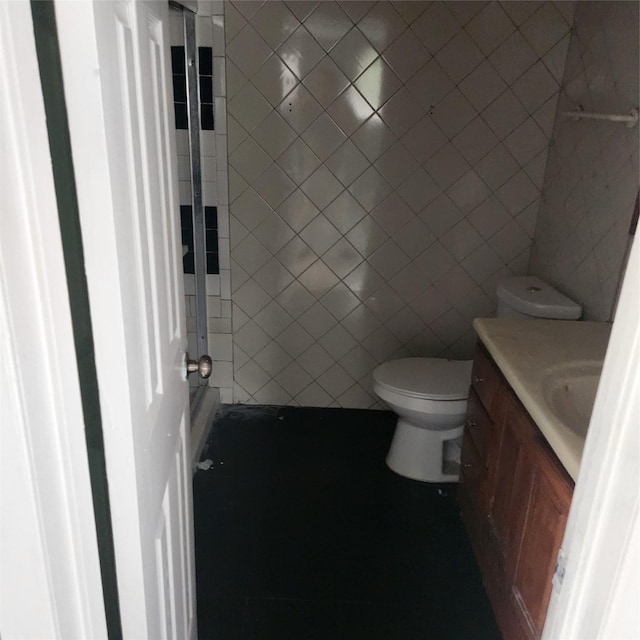 bathroom featuring toilet, tile walls, and vanity