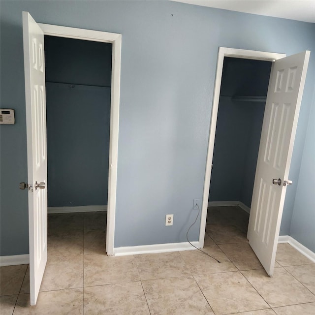 unfurnished bedroom with a spacious closet, light tile patterned floors, baseboards, and a closet