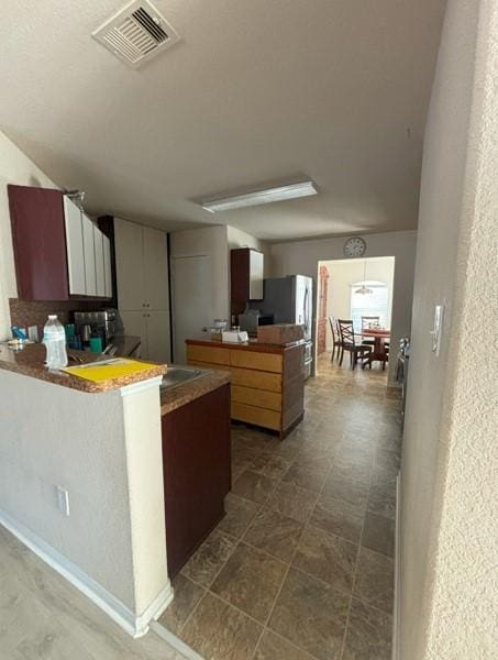 kitchen with visible vents, a peninsula, and freestanding refrigerator