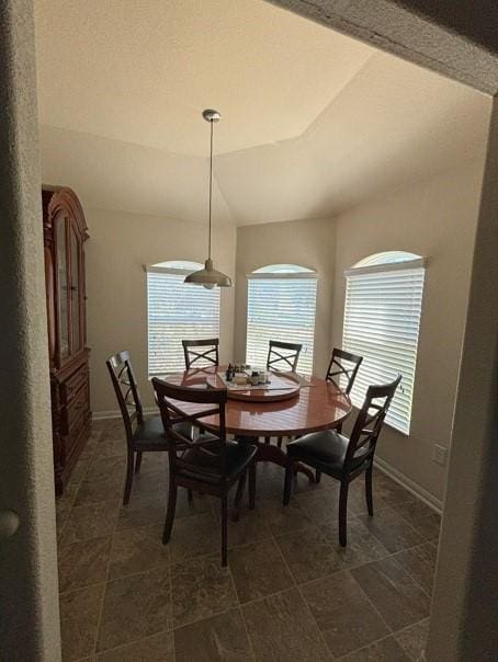 dining space featuring lofted ceiling and baseboards