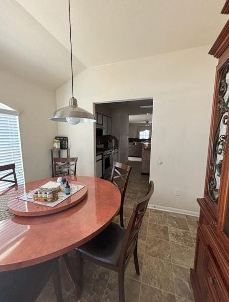 dining space with a wealth of natural light, baseboards, and vaulted ceiling