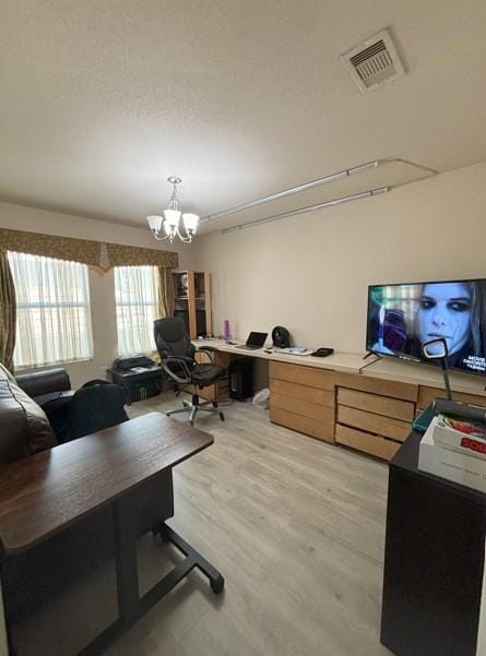 office space featuring visible vents, light wood-style floors, a chandelier, and a textured ceiling