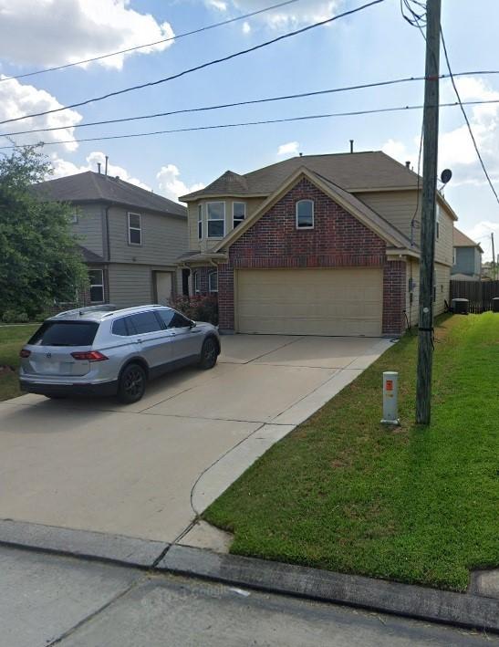 traditional-style house featuring concrete driveway, a garage, brick siding, and a front lawn