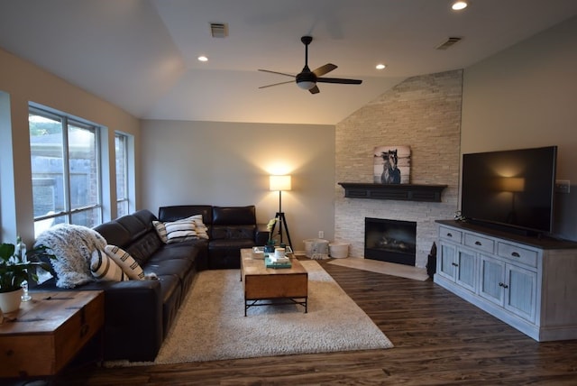 living room featuring visible vents, dark wood-type flooring, recessed lighting, a stone fireplace, and vaulted ceiling