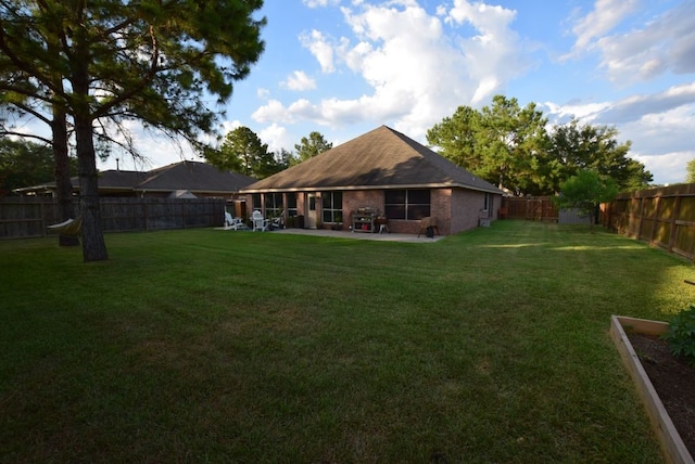 back of house with a patio area, a yard, a fenced backyard, and brick siding