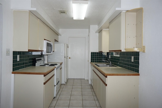 kitchen featuring visible vents, a sink, white cabinetry, white appliances, and light tile patterned floors