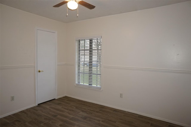 spare room featuring baseboards, dark wood finished floors, and a ceiling fan