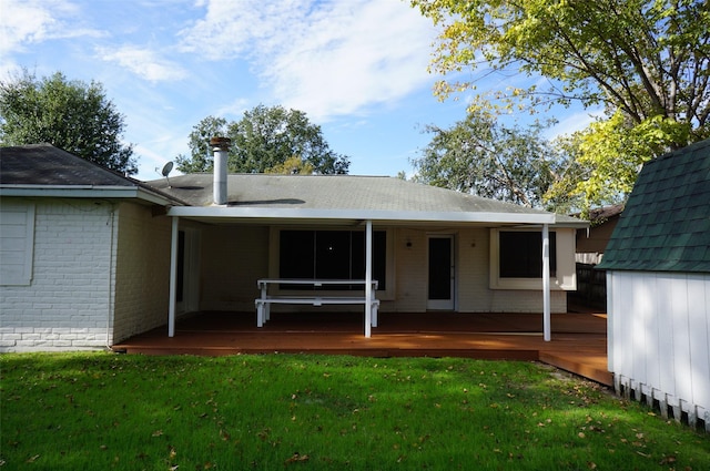 back of property with brick siding, a deck, and a yard