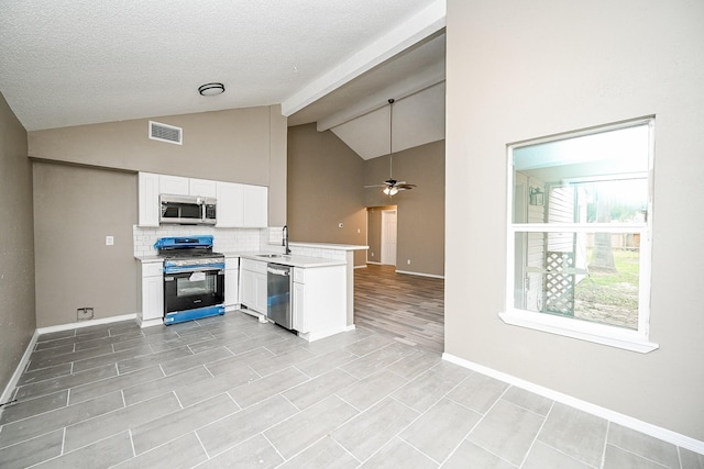 kitchen featuring visible vents, light countertops, a peninsula, stainless steel appliances, and a sink