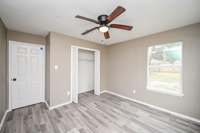 unfurnished bedroom featuring baseboards, light wood-style flooring, a closet, a textured ceiling, and a ceiling fan