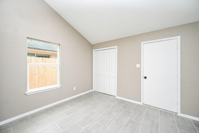 unfurnished bedroom with baseboards, lofted ceiling, and a closet