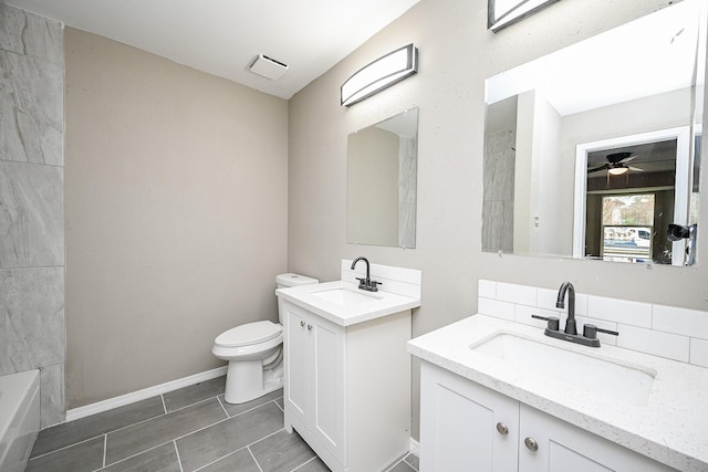 full bathroom with a sink, baseboards, toilet, and two vanities