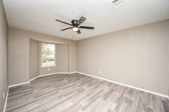 empty room with visible vents, ceiling fan, baseboards, light wood-style floors, and a textured ceiling