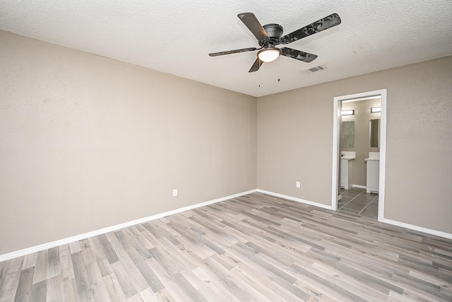 empty room featuring a ceiling fan, baseboards, visible vents, light wood finished floors, and a textured ceiling