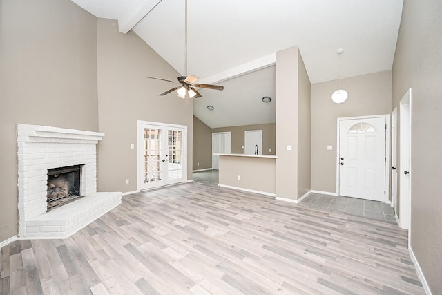 unfurnished living room with a brick fireplace, a ceiling fan, light wood-type flooring, and baseboards