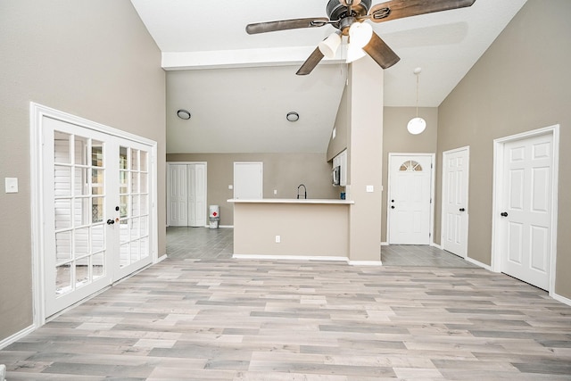 kitchen featuring light wood-style flooring, french doors, baseboards, and high vaulted ceiling