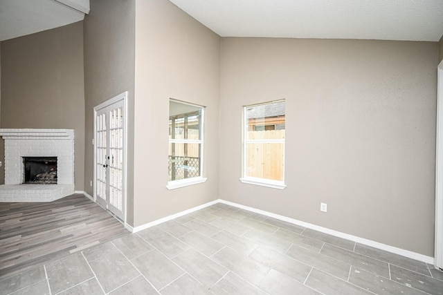 interior space with baseboards, high vaulted ceiling, and a fireplace