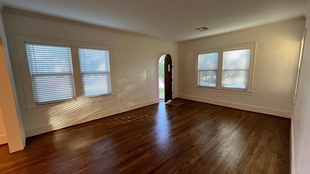 interior space featuring baseboards, visible vents, arched walkways, ornamental molding, and dark wood-type flooring