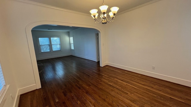 spare room with dark wood-style floors, arched walkways, an inviting chandelier, crown molding, and baseboards