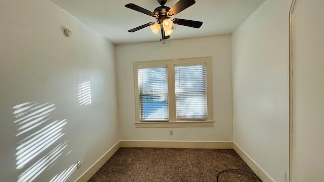 empty room with baseboards, dark colored carpet, and ceiling fan