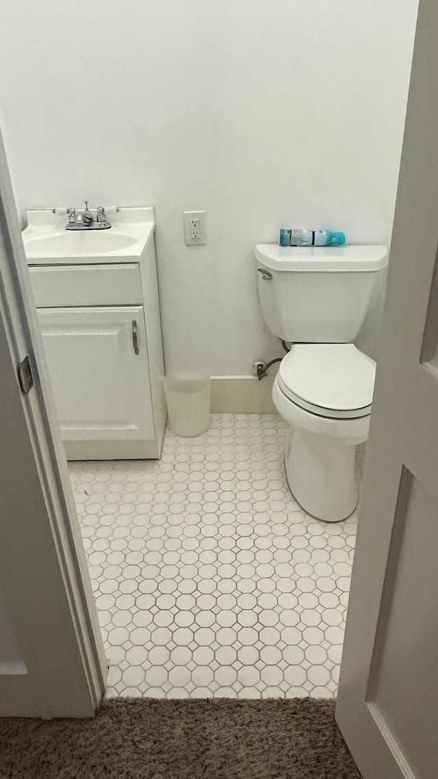 half bath featuring baseboards, toilet, and vanity