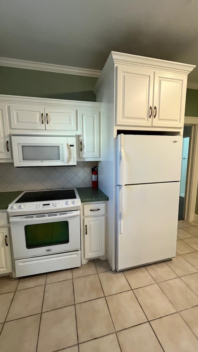 kitchen with ornamental molding, dark countertops, tasteful backsplash, white appliances, and light tile patterned flooring