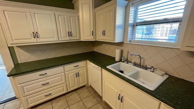 kitchen featuring light tile patterned floors, white dishwasher, a sink, white cabinetry, and backsplash