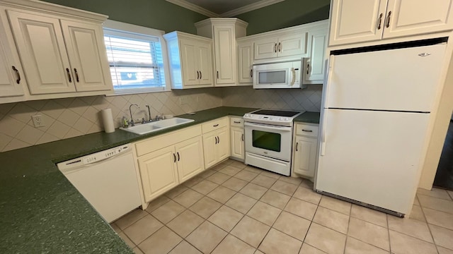 kitchen with white appliances, light tile patterned floors, dark countertops, a sink, and crown molding