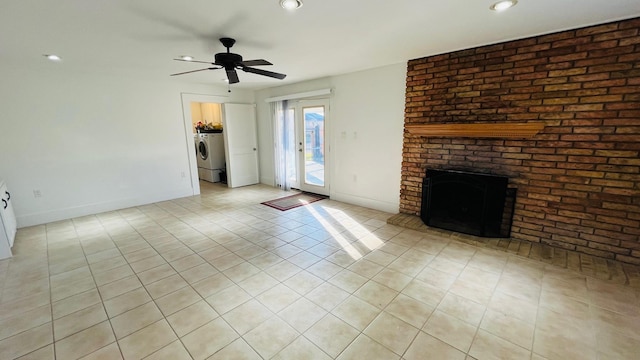 unfurnished living room with a ceiling fan, washer / clothes dryer, light tile patterned floors, baseboards, and a brick fireplace