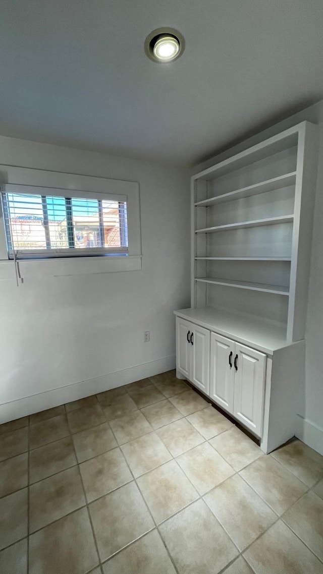 spare room with light tile patterned flooring and baseboards