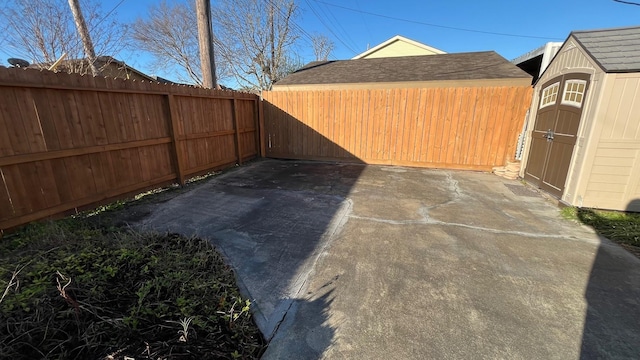 view of yard with an outbuilding, a fenced backyard, a shed, and a patio area