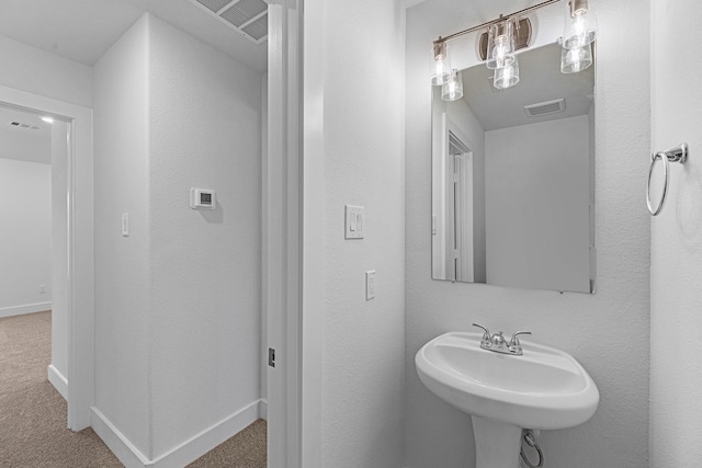 bathroom with baseboards, visible vents, and a sink