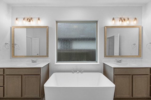 bathroom featuring a sink, a freestanding bath, and a healthy amount of sunlight